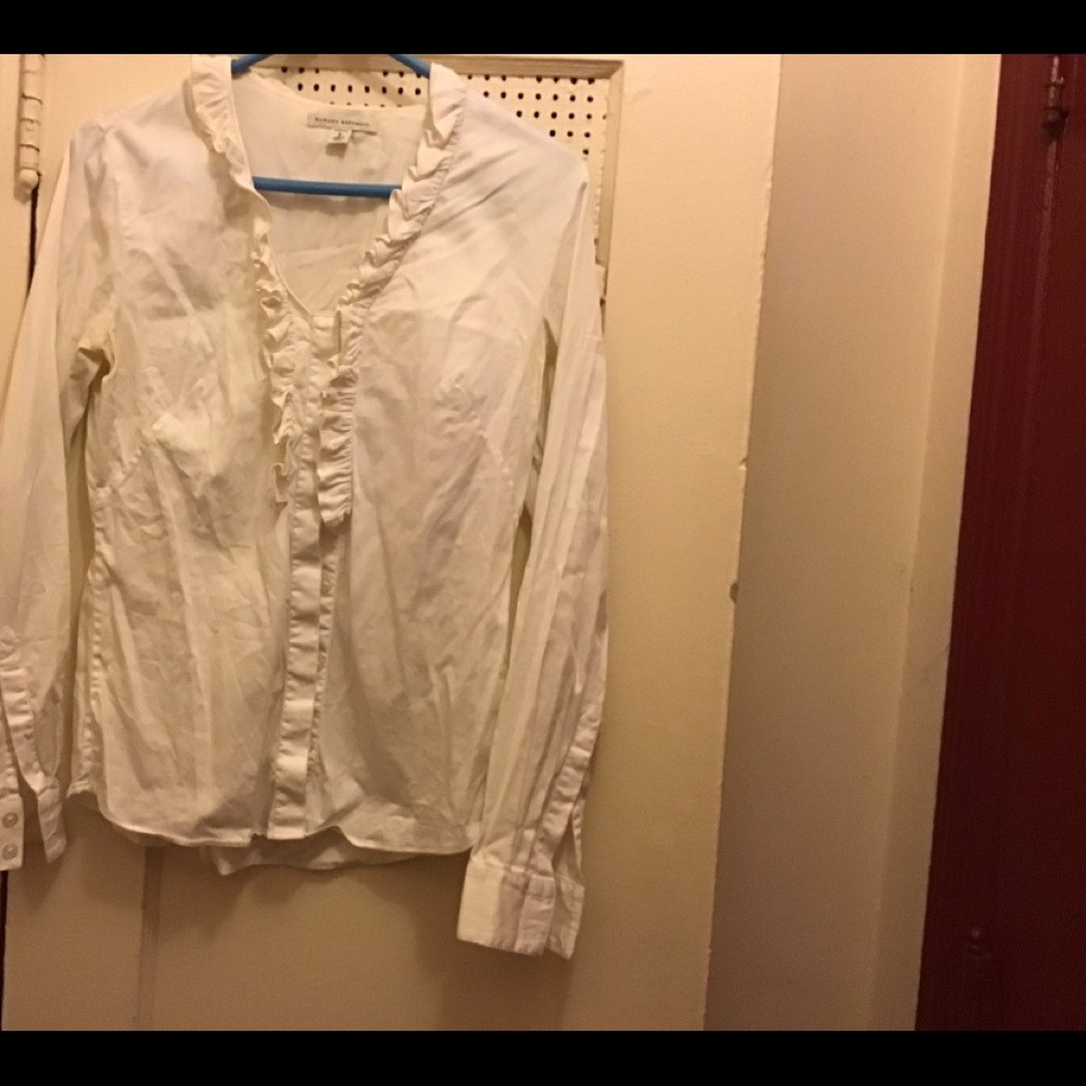 White blouse with ruffle around the collar halfway down the front. Stretch)